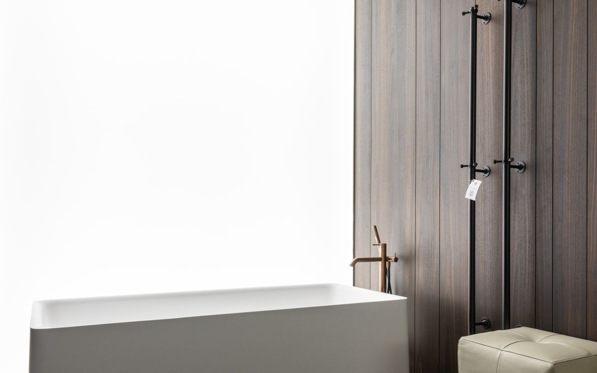Baignoire épurée devant un mur en bois fumé avec robinetterie laiton